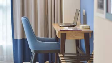 A modern room with a wooden desk, a laptop, and a blue chair.