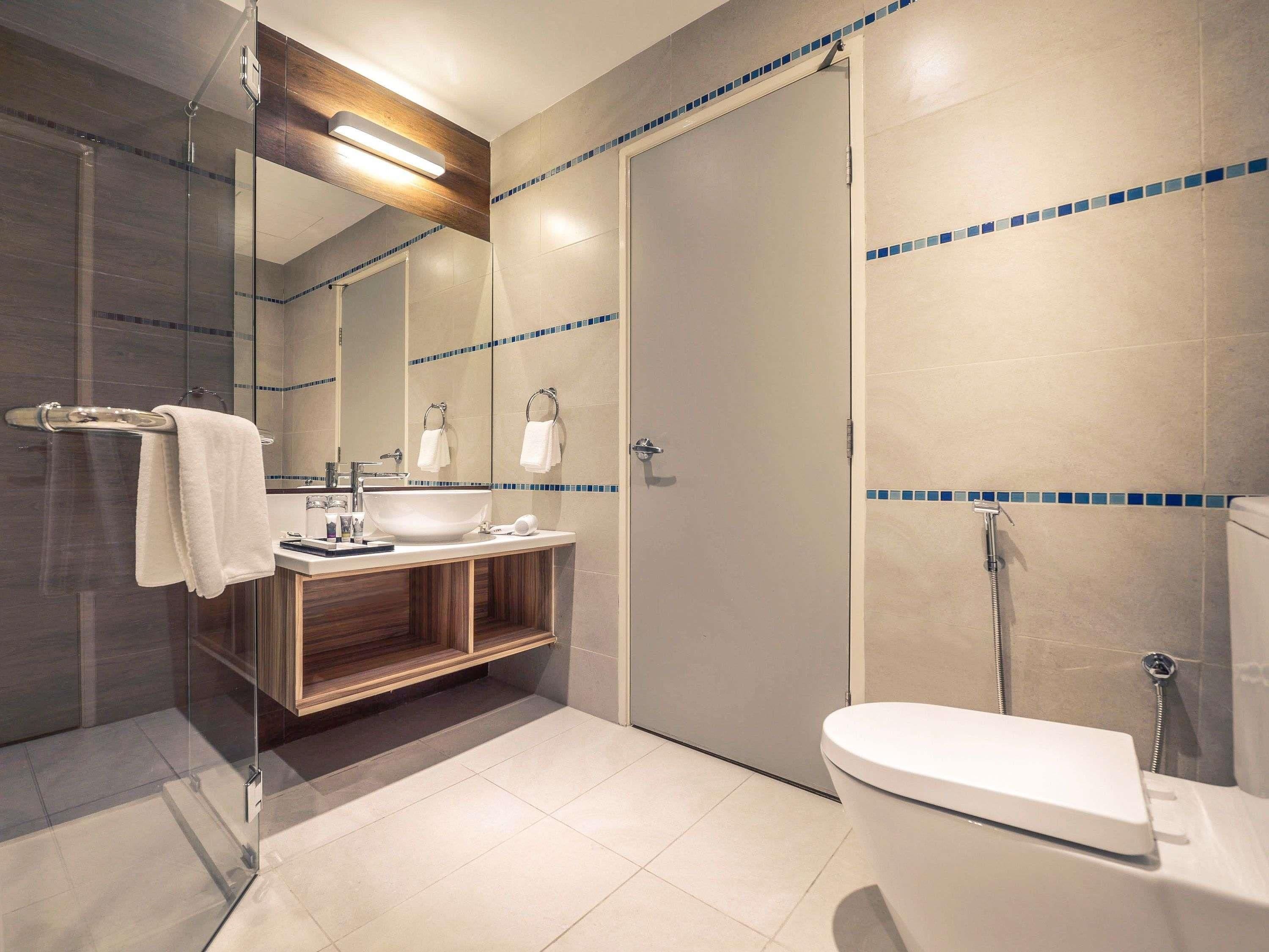 Un baño moderno con ducha envuelta en vidrio, un lavabo blanco y un inodoro.