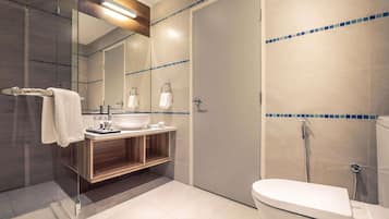 Un baño moderno con ducha envuelta en vidrio, un lavabo blanco y un inodoro.