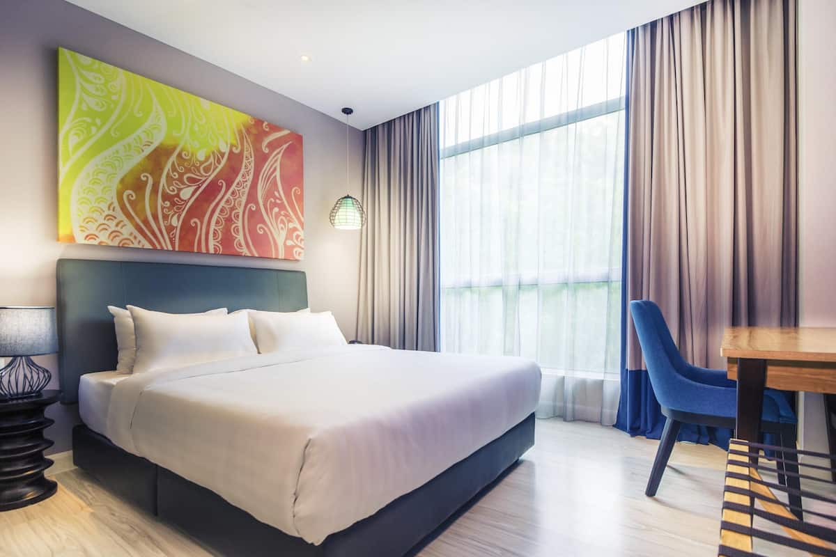 A hotel room with a large bed, a desk, and a chair.