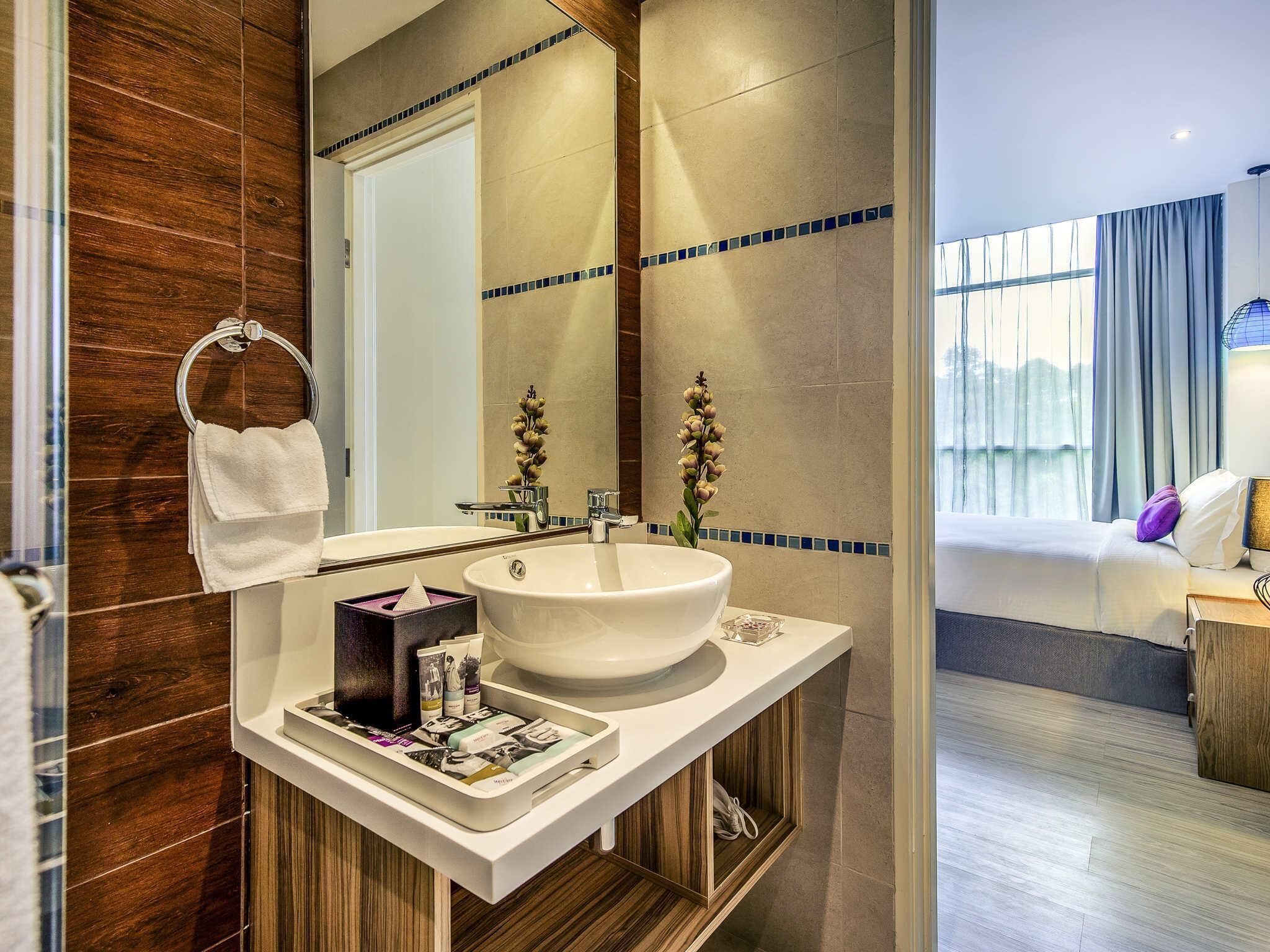 A modern bathroom with a large sink, a mirror, and a wooden vanity.