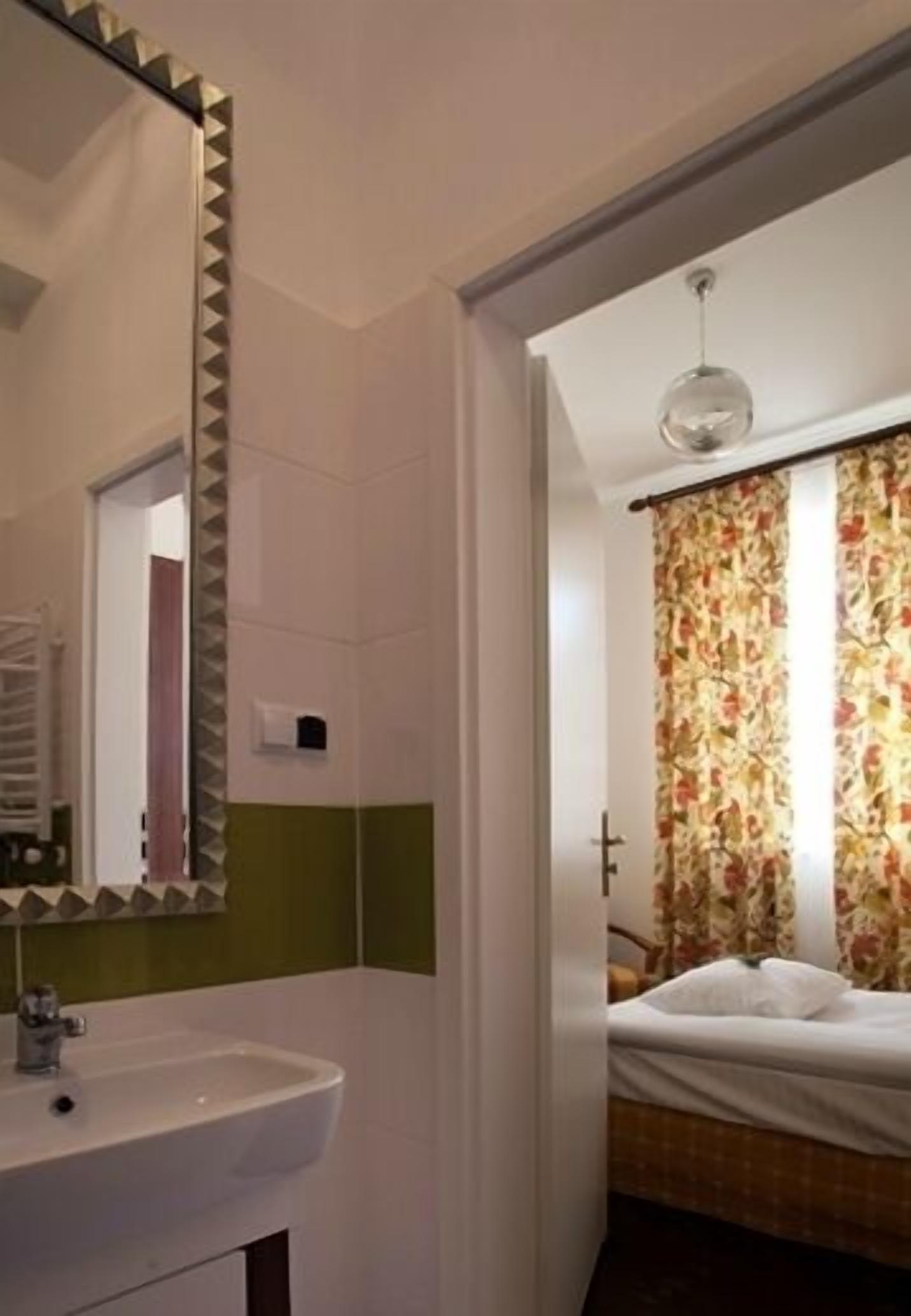A bathroom with a white sink, mirror, and green-tiled walls.