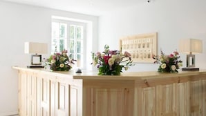 Una mesa de recepción con detalles de madera, dos lámparas y arreglos florales.