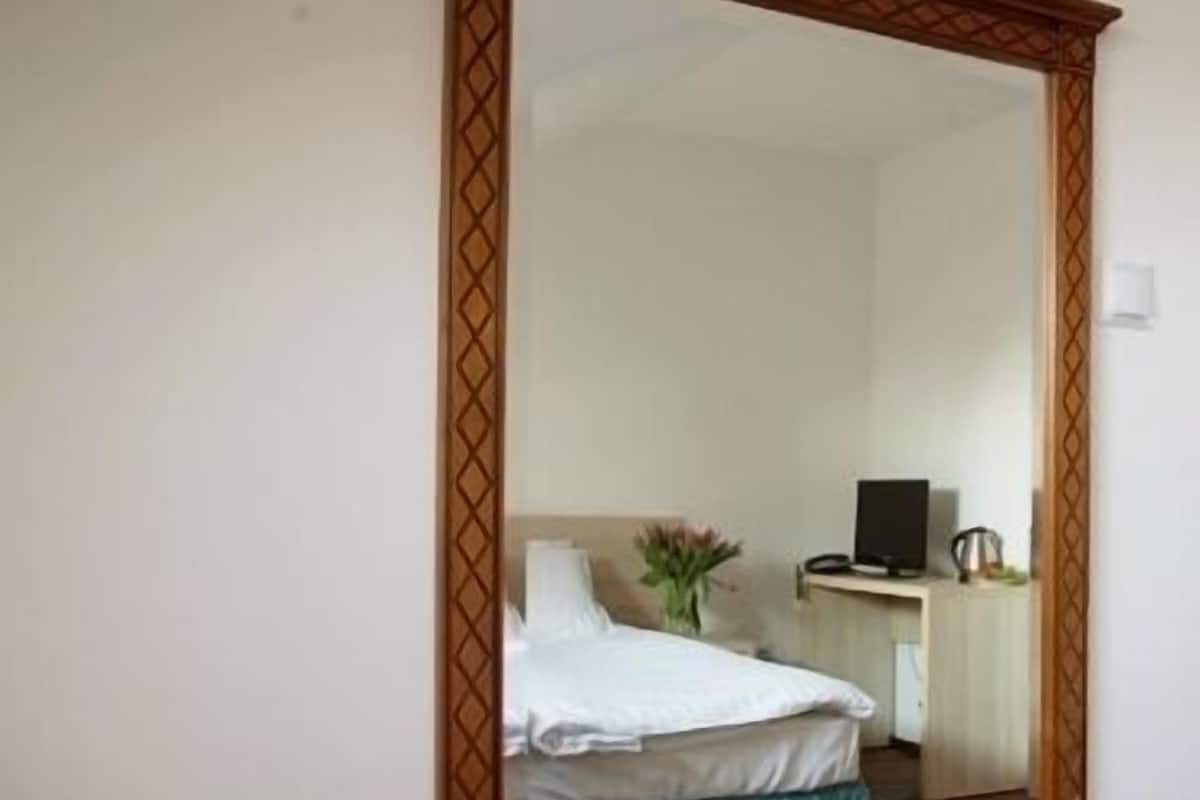 Un dormitorio con cama, escritorio, silla y un espejo grande en la pared.