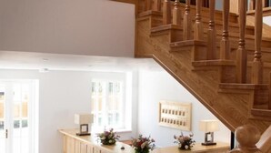 Una escalera de madera con piso de tablones y un mostrador de recepción decorado con flores.