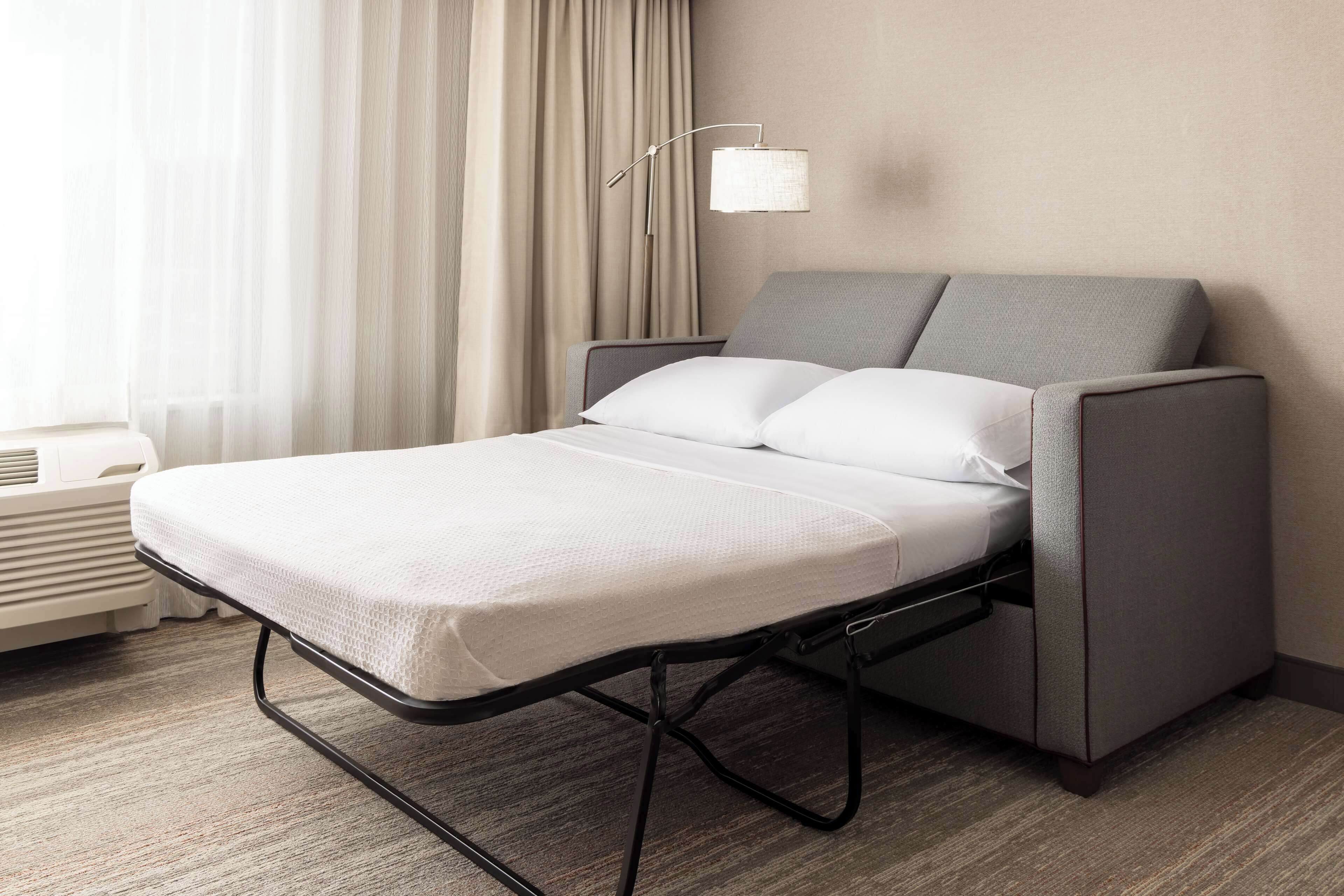 A neatly made bed with a grey headboard and footboard, a white mattress, and a black metal frame.