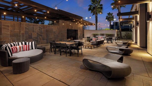 An outdoor patio with stone flooring, wicker furniture, and string lights.