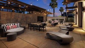 An outdoor patio with stone flooring, wicker furniture, and string lights.