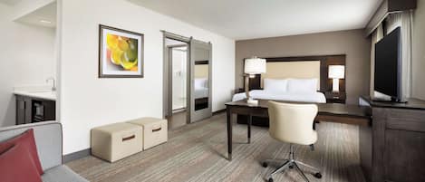 Una habitación de hotel con cama, escritorio, silla, televisor y sofá.