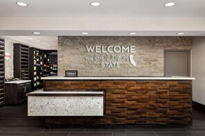A reception desk with a "Welcome to the Golden State" sign, a minibar, and a "Hilton Honors" sign.