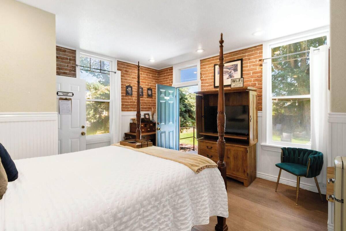 A bedroom with a bed, a wooden wardrobe, a television, and a blue door.