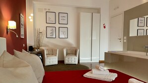 A hotel room with a red carpet, two white armchairs, a bed, a large mirror, and framed motivational quotes on the wall. - Le Coq Suites (Rome)