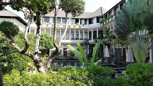 A hotel courtyard with lush greenery, outdoor seating, and a multi-story building with balconies. - Ompil Angkor Residence (Siem Reap)