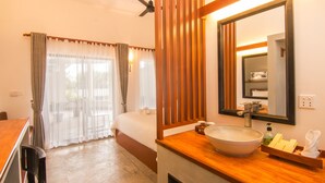 A hotel room with a bed, a wooden vanity with a large bowl sink, a mirror, and a ceiling fan. - Ompil Angkor Residence (Siem Reap)