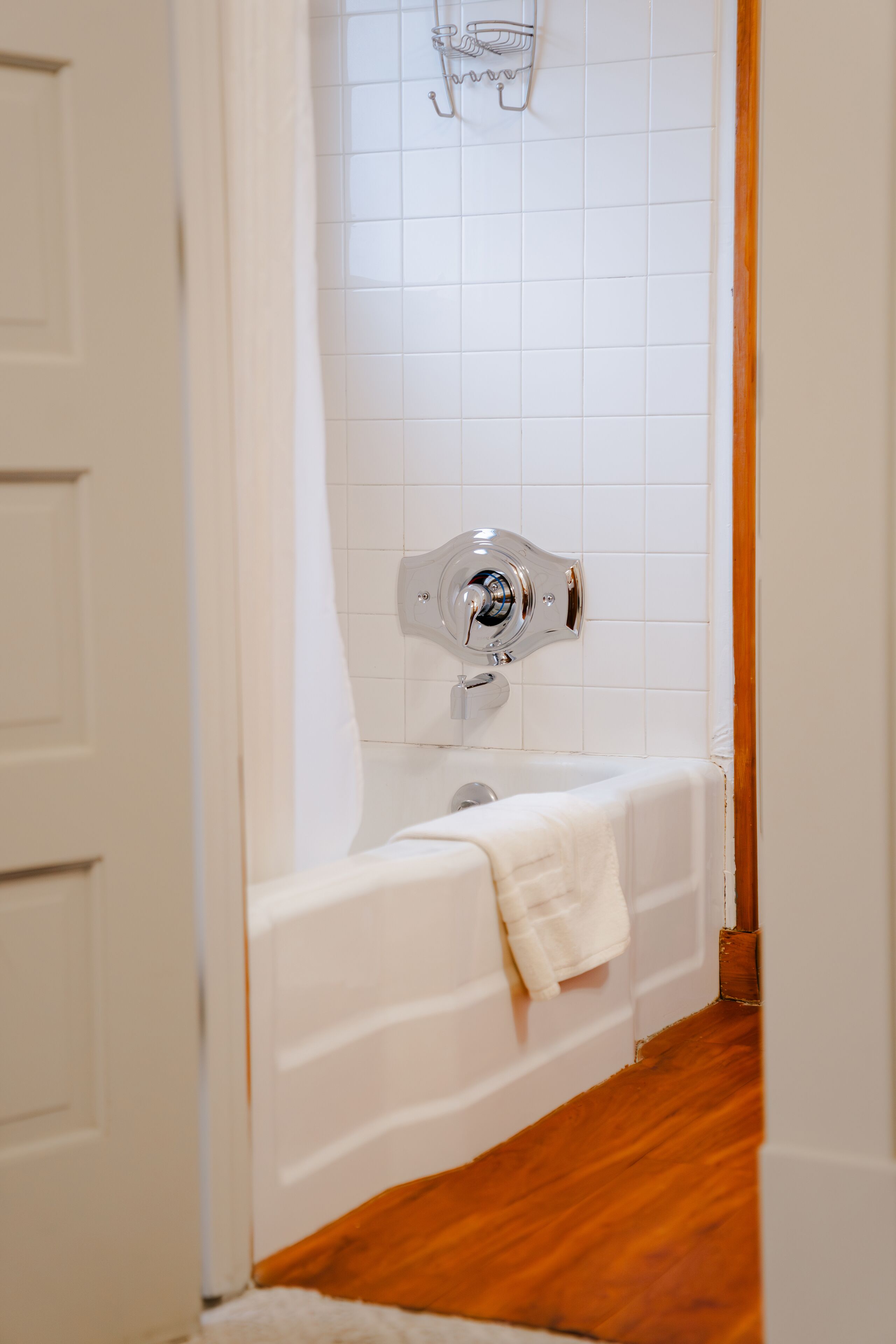 Un baño con una bañera blanca, un cabezal de ducha y una toalla colgada en la pared.
