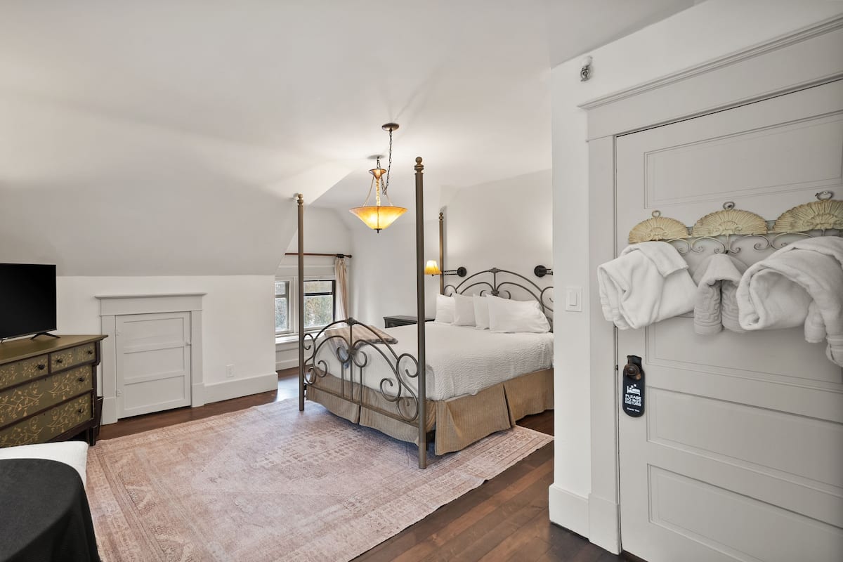 A bedroom with a four-poster bed, a television, a lamp, and a wardrobe.