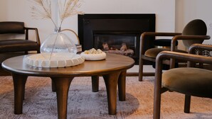 Un salon moderne avec une cheminée, une table basse ronde en bois et des sièges confortables.