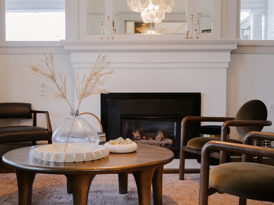 Un salon moderne avec une cheminée, une table basse ronde en bois et des sièges confortables.