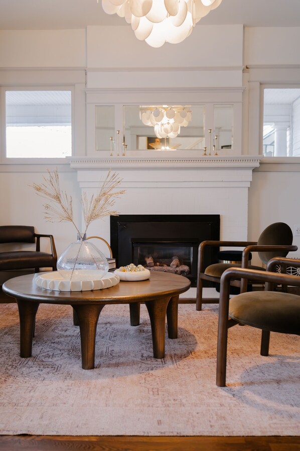 A modern living room with a fireplace, round wooden coffee table, and comfortable seating. - Greenbriar Inn (Coeur d'Alene)