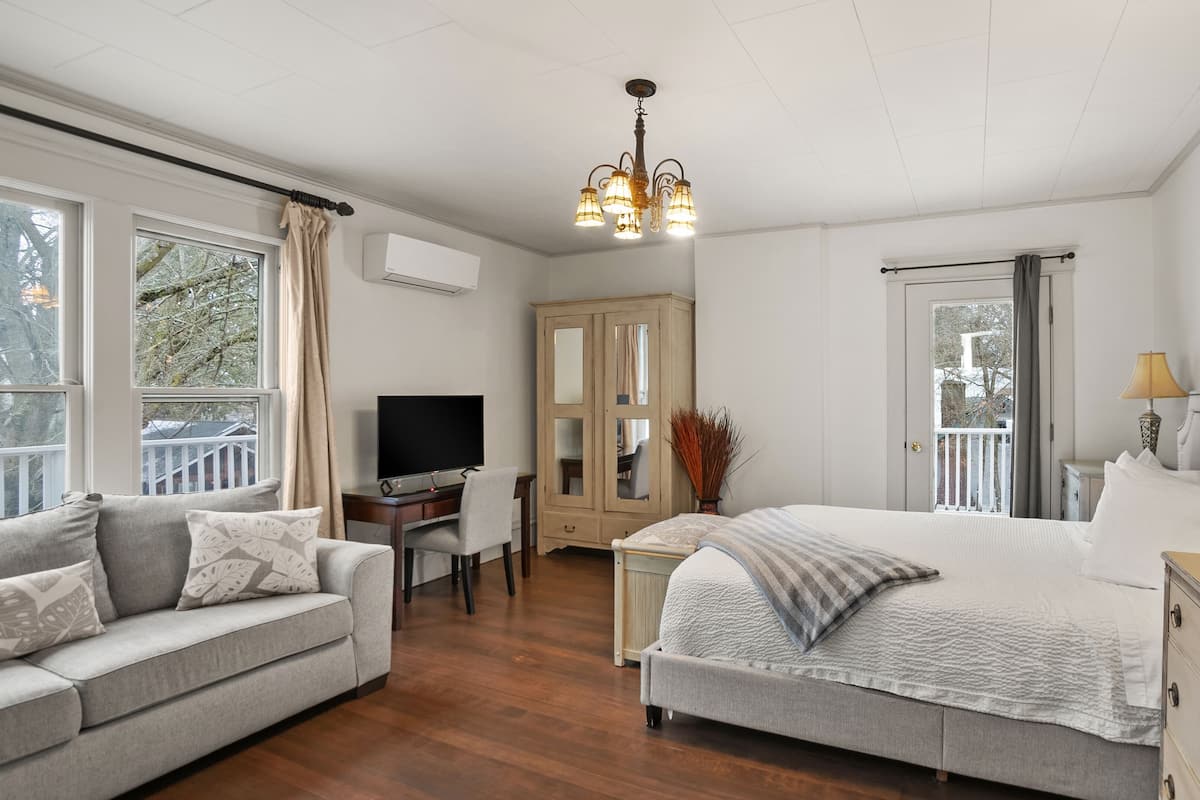 A bedroom with a bed, a desk, a television, a sofa, and a wardrobe.