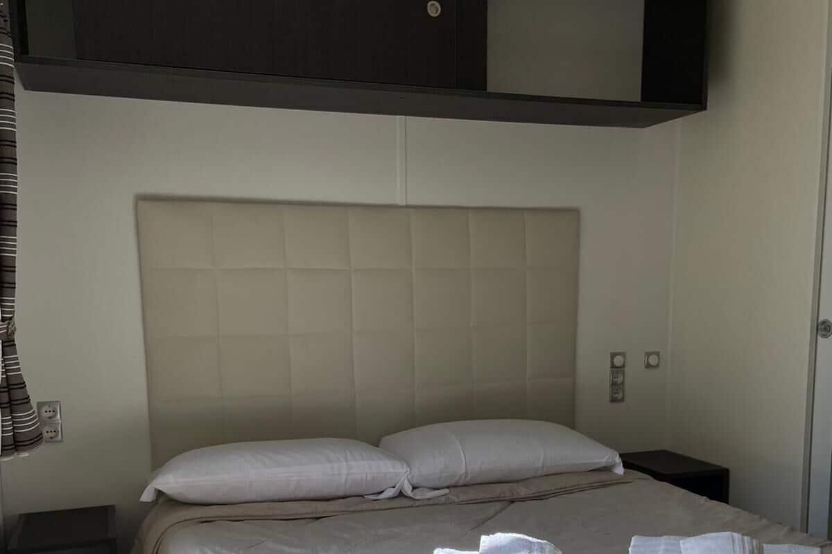 Een hotelkamer met een groot bed, een hoofdeinde en een donker houten paneel erboven.