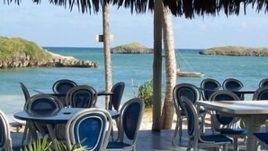 An outdoor seating area with tables and chairs, overlooking a beach and the sea. - Watamu Palm Beach (Watamu)
