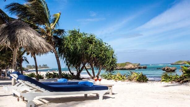 A beachside lounge with a white frame, blue cushions, and two glasses of red drink. - Watamu Palm Beach (Watamu)