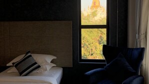 Una habitación de hotel con una cama, una silla y una ventana con vistas a un templo.