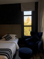 Una habitación de hotel con una cama, una silla y una ventana con vistas a un templo.