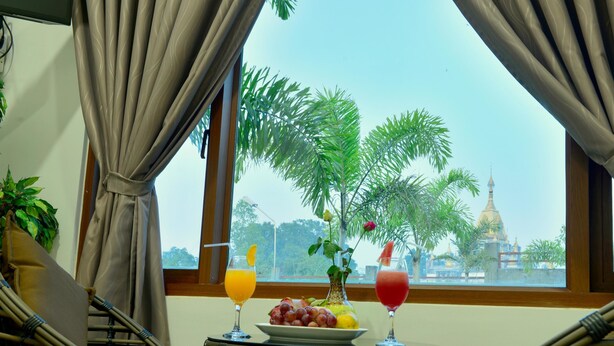 Una habitación con vistas a un templo, una mesa con frutas y bebidas, y mobiliario de mimbre.