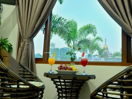 Una habitación con vistas a un templo, una mesa con frutas y bebidas, y mobiliario de mimbre.