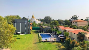 Zona residencial con piscina, un edificio blanco de grandes dimensiones con una aguja dorada y vegetación circundante.
