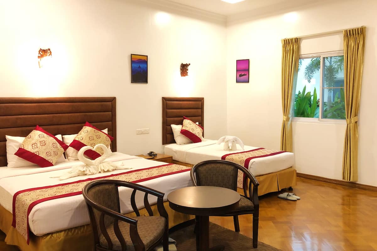 Une chambre d’hôtel avec deux lits, une table ronde et une chaise.