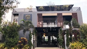 Un edificio moderno con un logotipo destacado, un balcón y una entrada con portón.