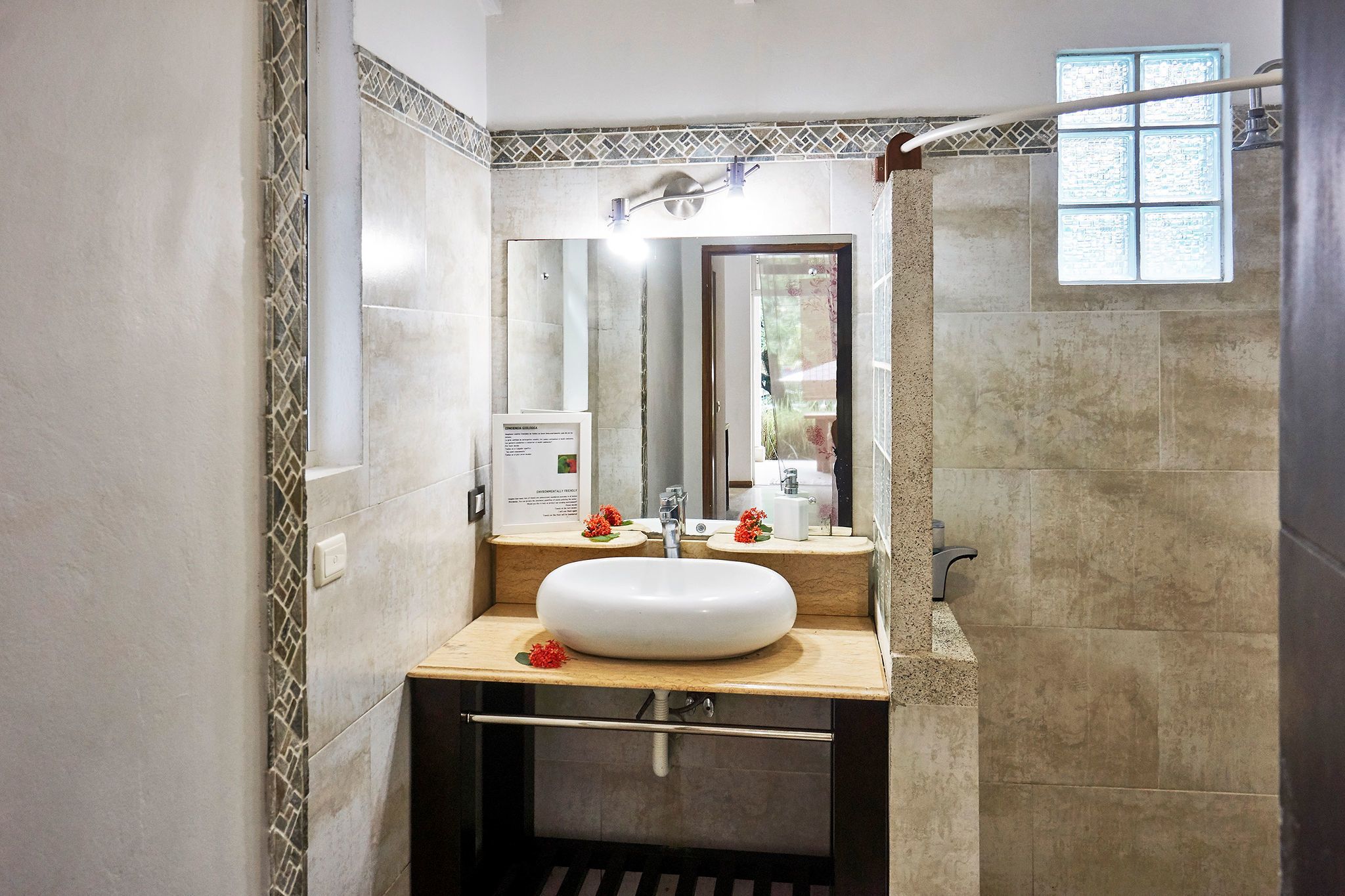 A bathroom with a large mirror, a white sink, and a shower area.