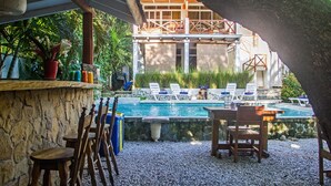 Un área de piscina con sillones de descanso, una mesa y un muro de piedra.