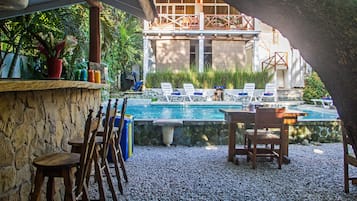 Una piscina al aire libre, sombrillas, sillones reclinables de piscina