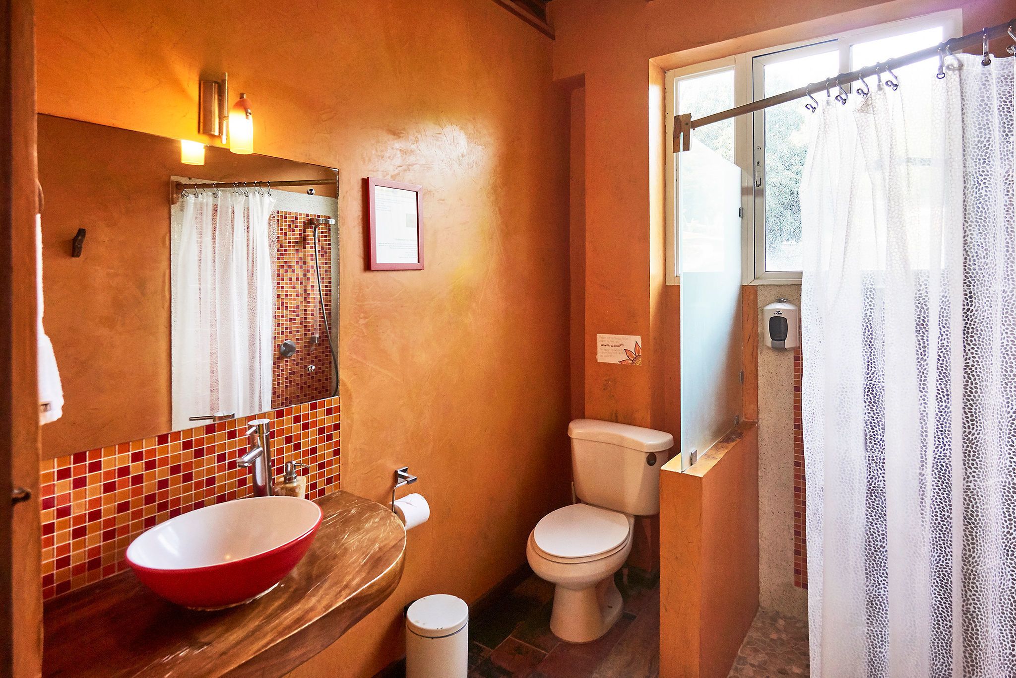 Ein Badezimmer mit einem roten Waschbecken, einer Toilette und einer Duschvorhang.