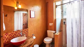 Un baño con lavabo rojo, inodoro y cortina de ducha.