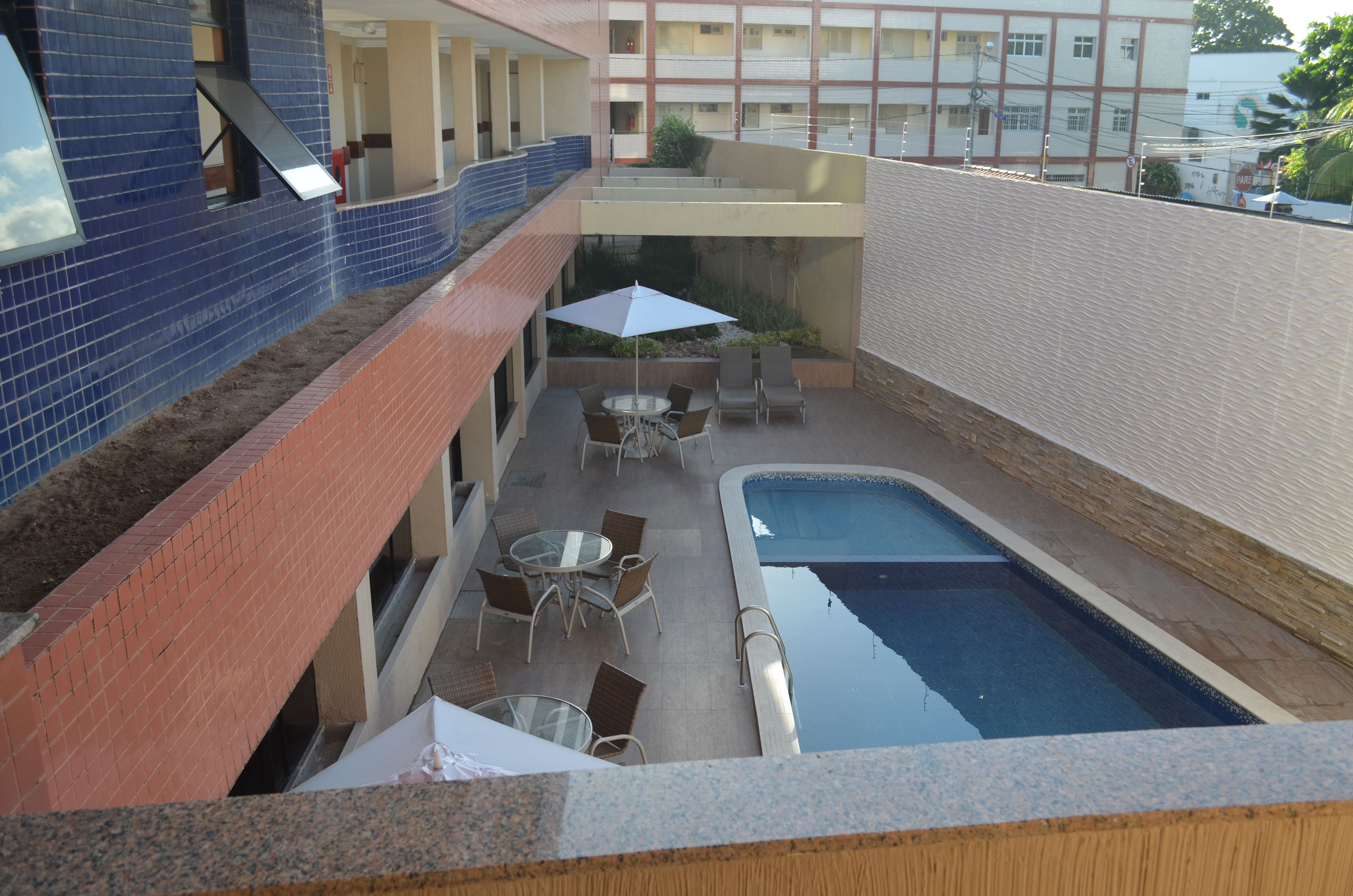 A rooftop pool area with a small pool, outdoor seating, and a view of the building's interior.