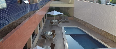A rooftop pool area with a small pool, outdoor seating, and a view of the building's interior.