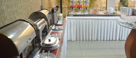 A buffet setup with a coffee station, hot and cold beverage dispensers, and a variety of food items.