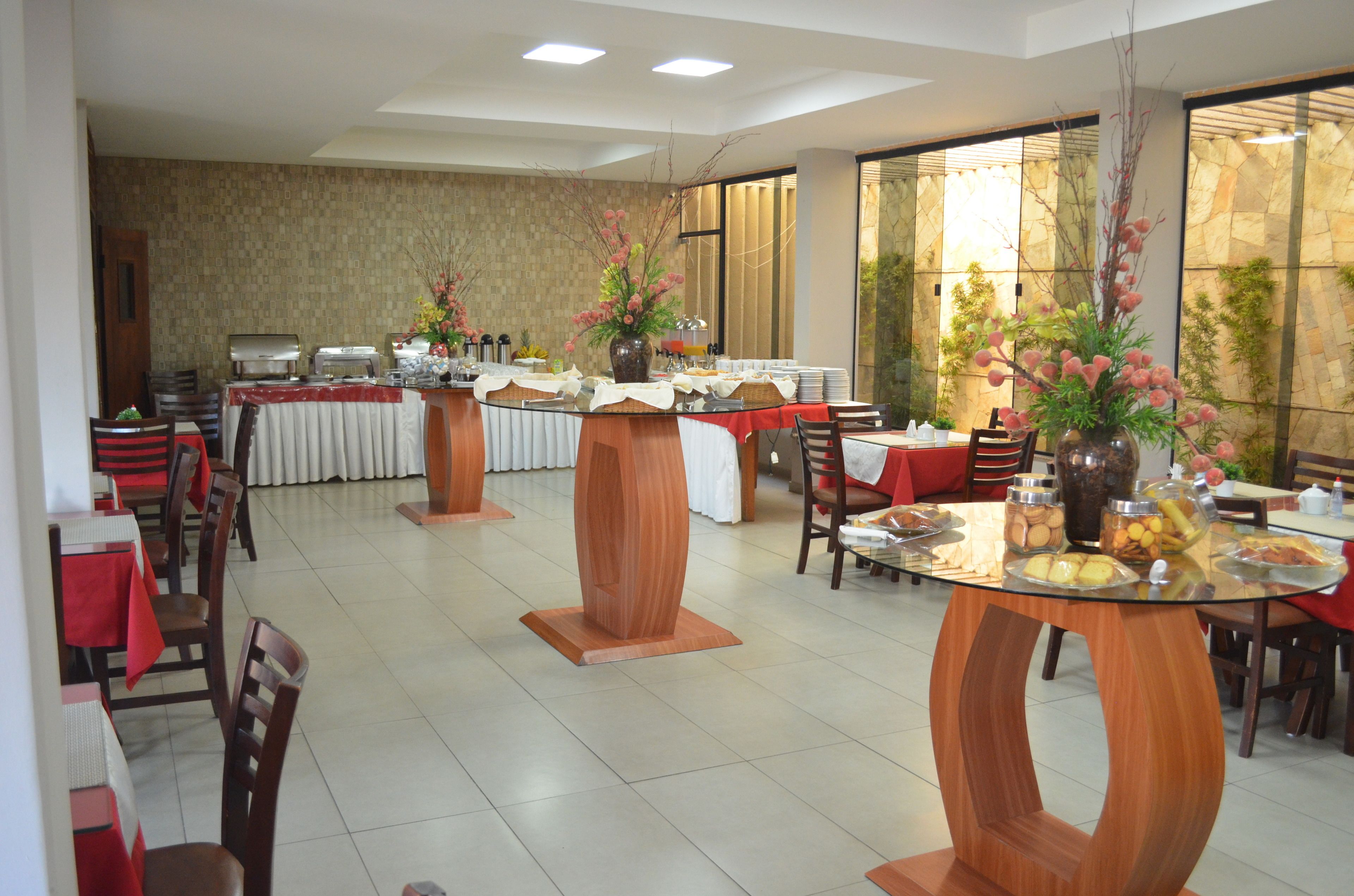 A dining area with multiple tables and chairs, a buffet setup, and decorative vases.