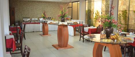 A dining area with multiple tables and chairs, a buffet setup, and decorative vases.