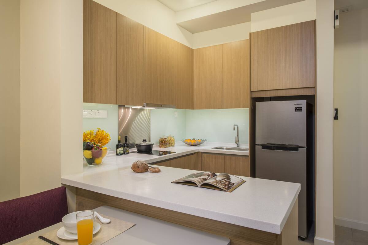 Eine moderne Küche mit Holzausstattung, einem Edelstahlkühlschrank und einer weißen Arbeitsplatte.