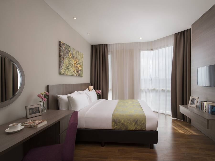 Een moderne hotelkamer met een groot bed, een bureau met stoel, een televisie en een raam met gordijnen.