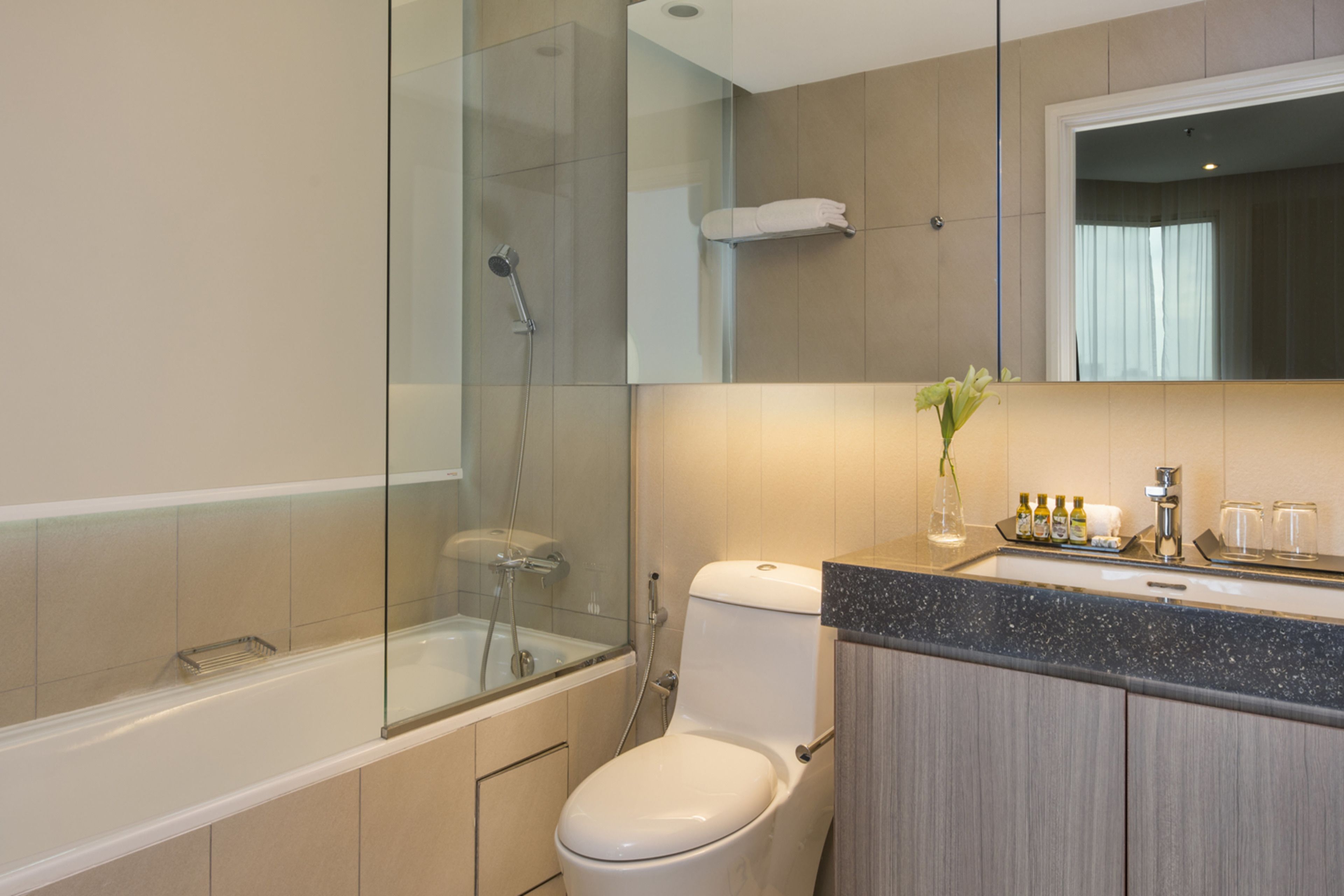 Un baño moderno con ducha envuelta en vidrio, inodoro blanco y tocador con espejo.