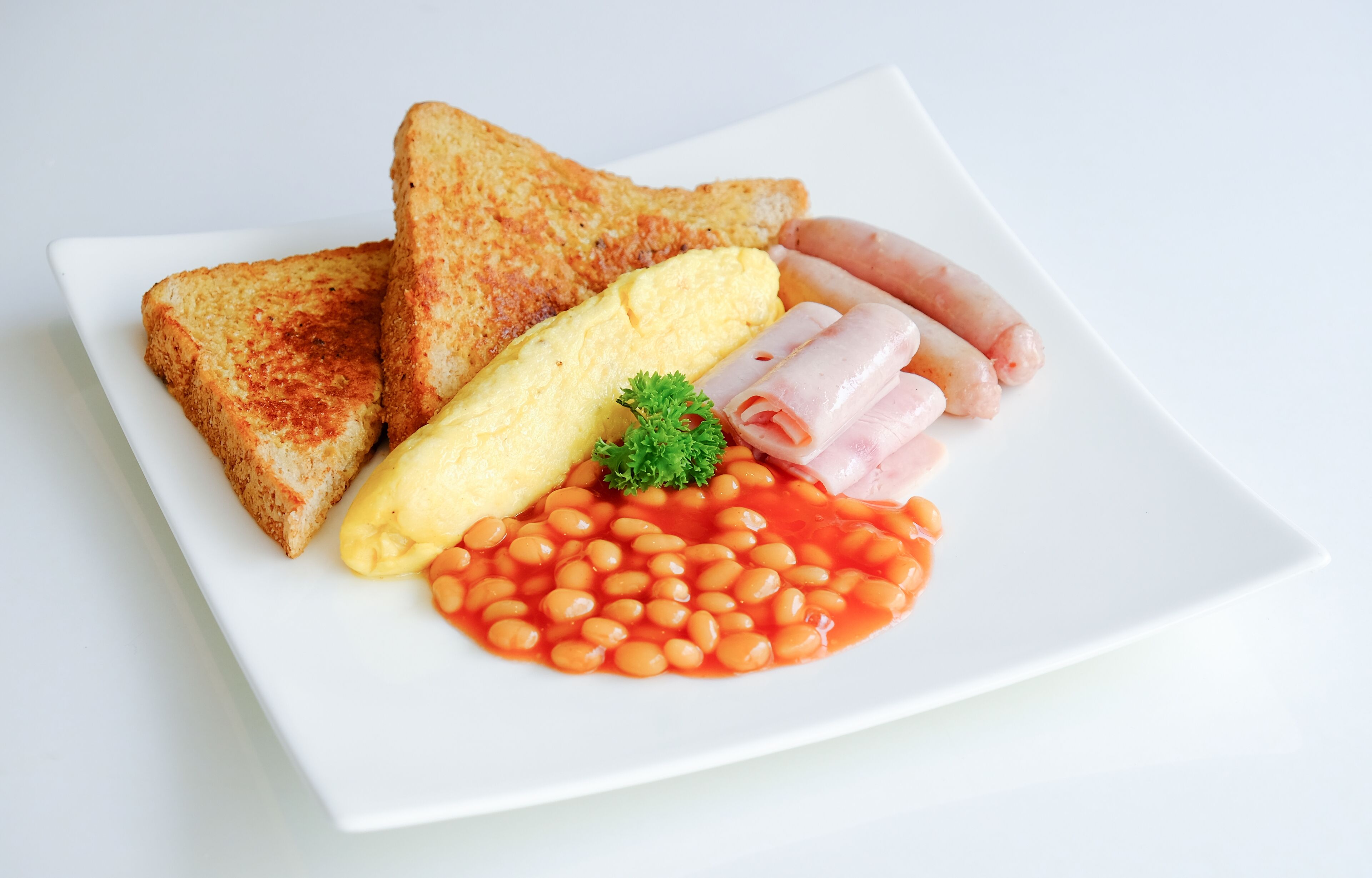 A plate with toast, eggs, sausages, and baked beans.