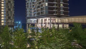 Un edificio de gran altura con múltiples balcones, un paseo cubierto y una zona de piscina.