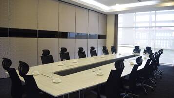 A conference room with a long table, black chairs, and a large window.